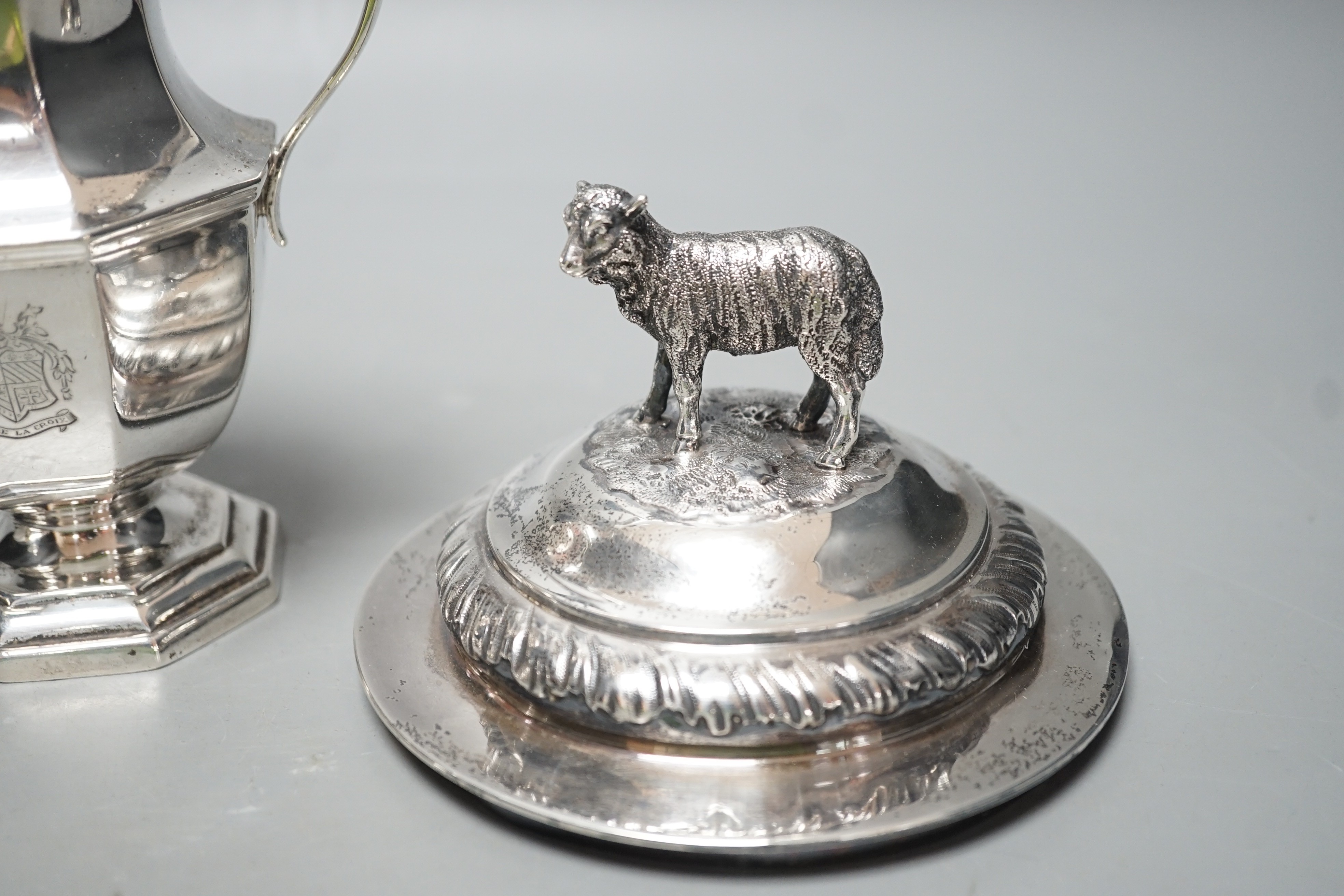 A 20th century silver cream jug by Mappin & Webb(date letter rubbed), height 13.9cm and two Victorian trophy cup covers, one with sheep finial, 24.8oz.